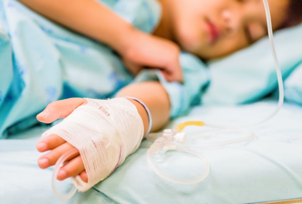 Closeup kid hand sleeps on a bed in hospital with saline intravenous.