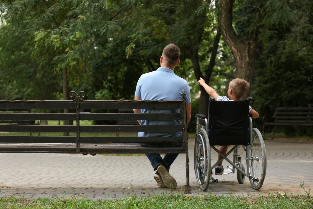 man with a boy in a wheelchair at the park