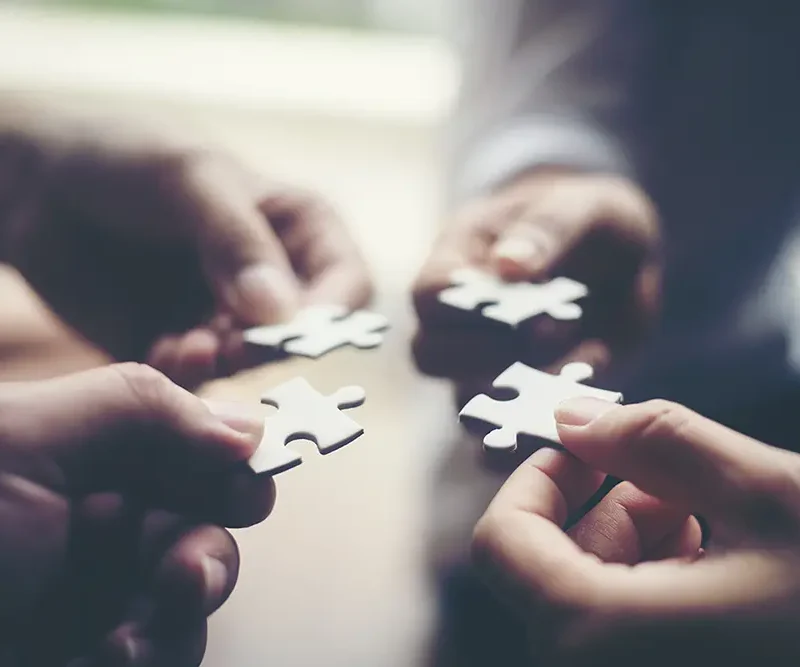 four people putting puzzle pieces together